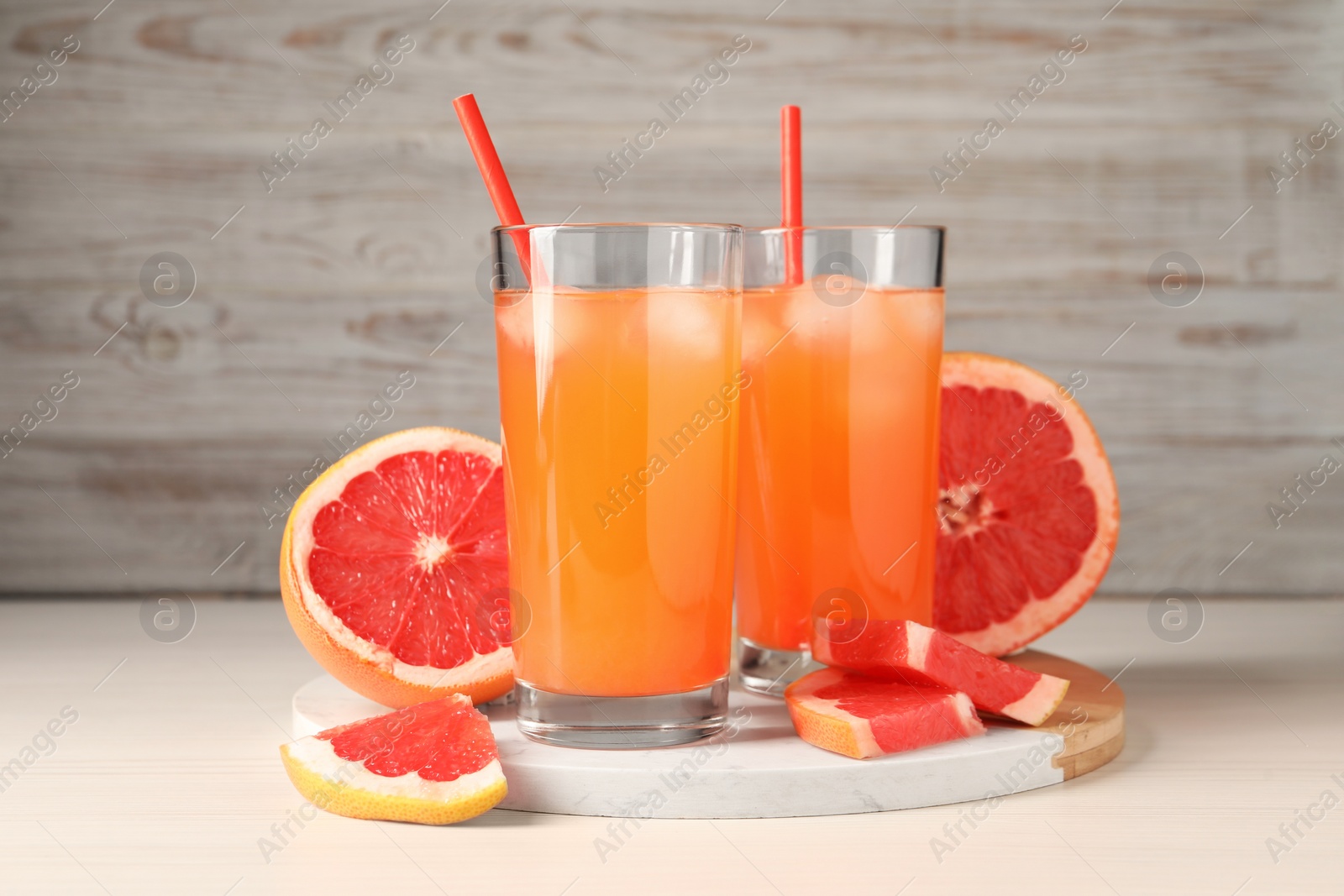 Photo of Tasty freshly made grapefruit juice and fruits on white wooden table