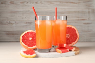 Photo of Tasty freshly made grapefruit juice and fruits on white wooden table