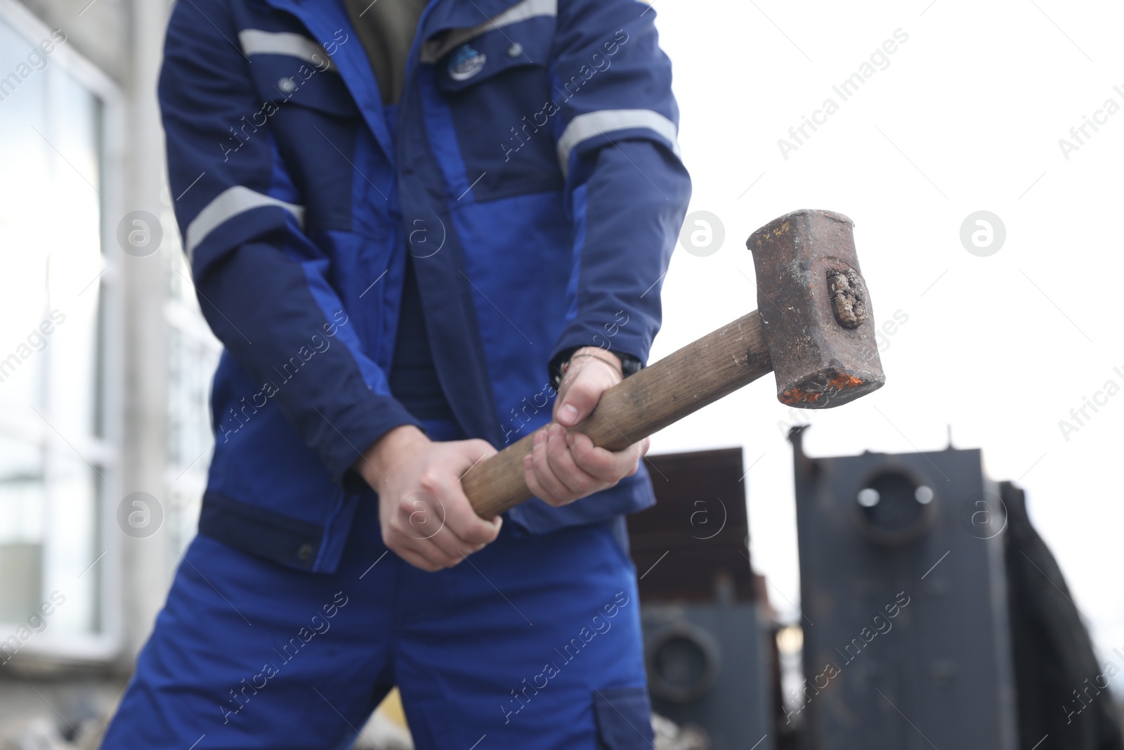 Photo of Man in uniform with sledgehammer outdoors, closeup