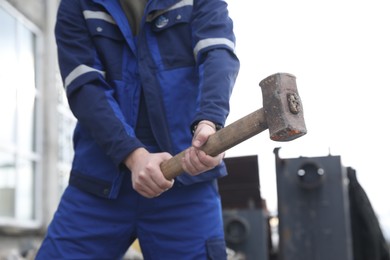 Man in uniform with sledgehammer outdoors, closeup