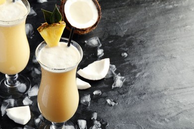 Photo of Tasty Pina Colada cocktails on dark table, space for text