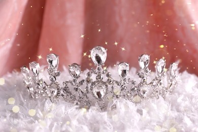 Image of Beautiful silver tiara with diamonds on white fluffy cloth, bokeh effect