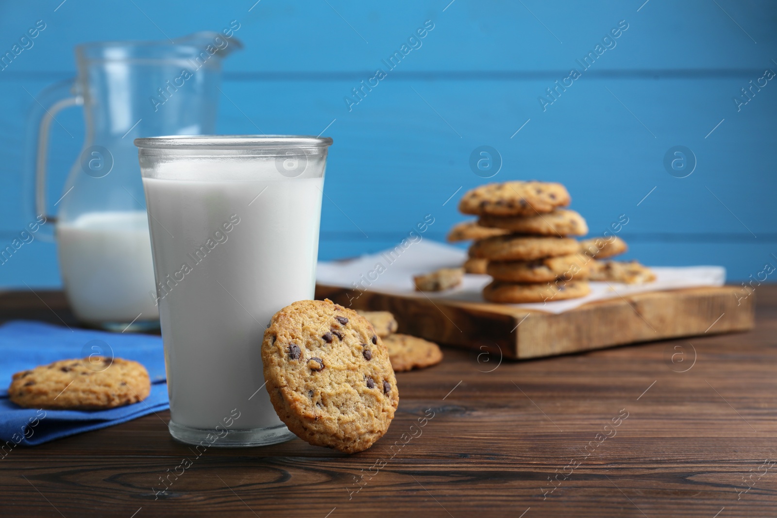 Delicious chocolate chip cookies and glass of milk on wooden table, space for text Photo of Delicious chocolate chip cookies and glass of milk on wooden table, space for text