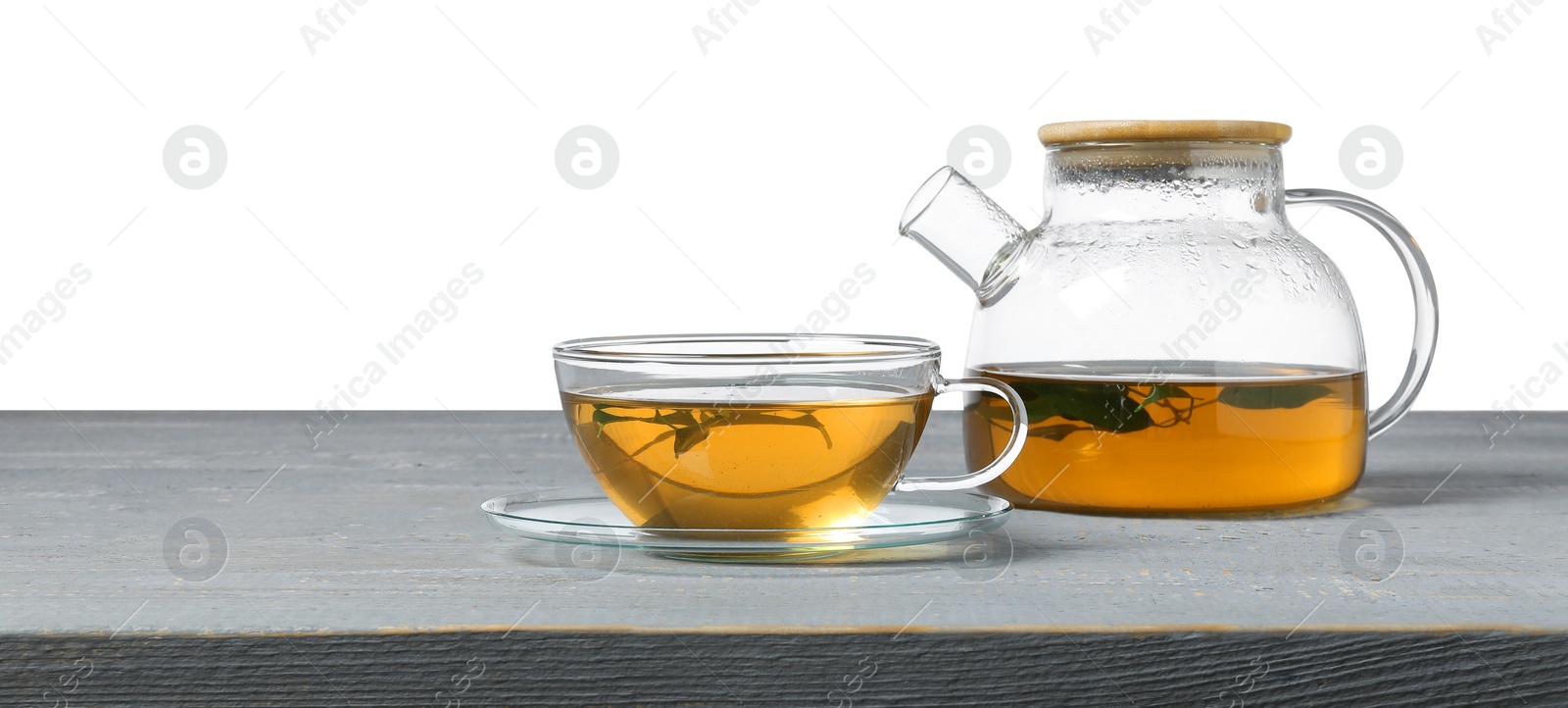 Photo of Refreshing green tea in cup and teapot on grey wooden table against white background