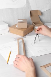 Photo of Man creating packaging design at light wooden table, closeup