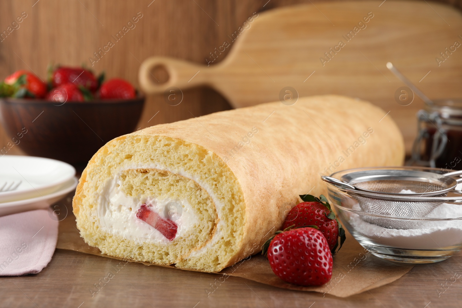 Photo of Delicious sponge cake roll with strawberries and cream on wooden table