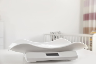 Photo of Modern digital baby scales on table in room. Space for text