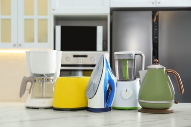 Photo of Set of modern home appliances on white marble table in kitchen