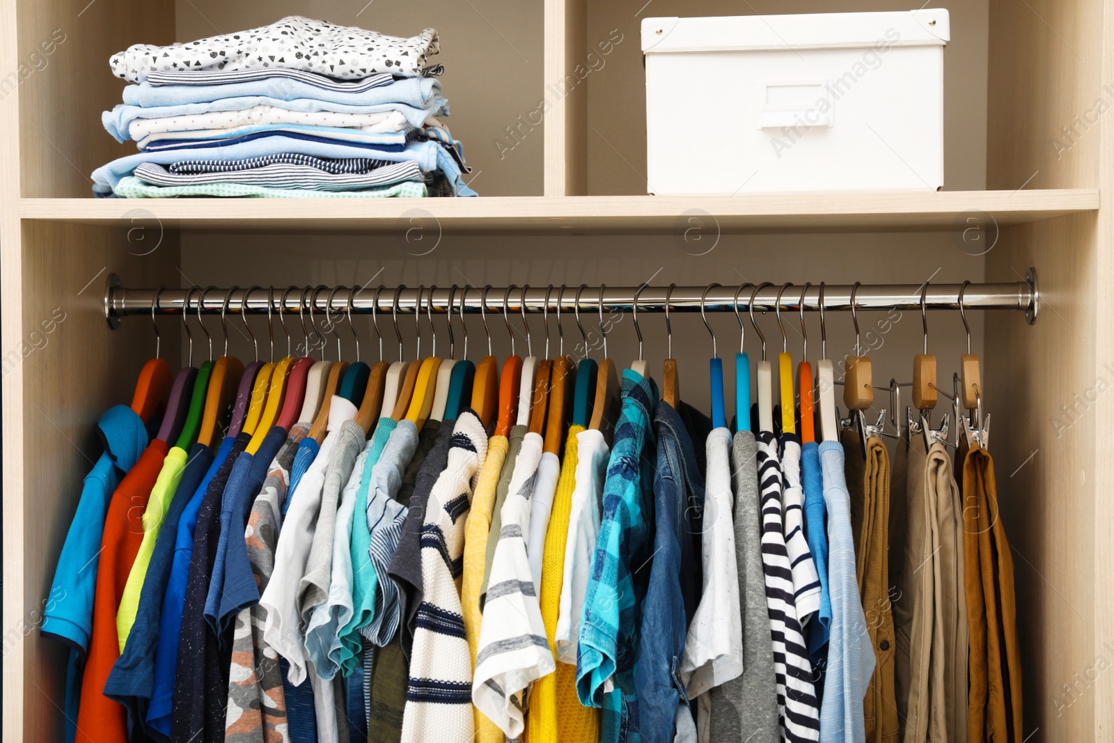 Photo of Hangers with teenage clothes on rack in wardrobe, closeup