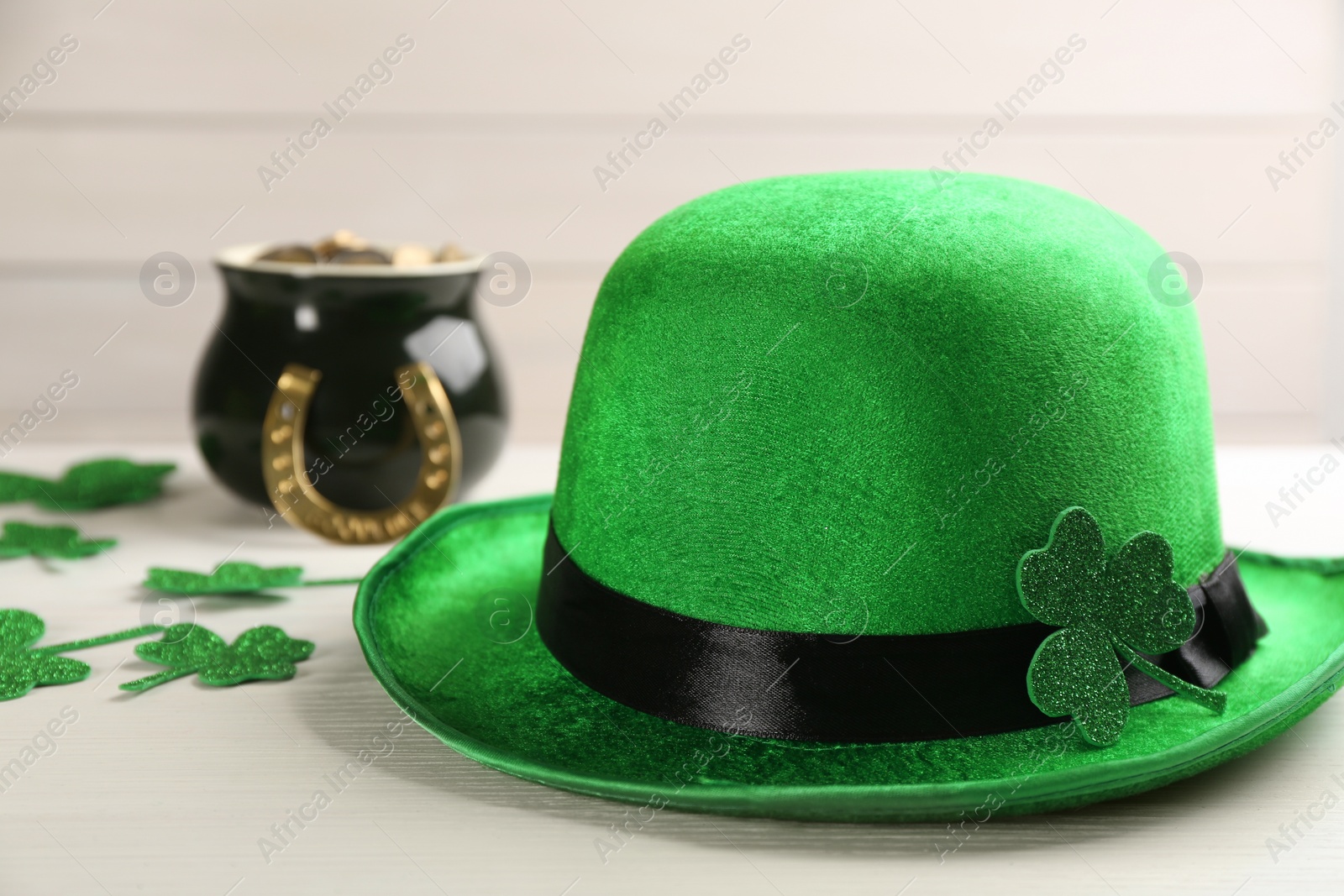 Photo of Leprechaun hat, decorative clover leaves and pot of gold on white wooden table, closeup. St Patrick's Day celebration