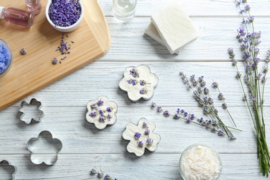 Flat lay composition of handmade soap bars with lavender flowers and ingredients on white wooden background