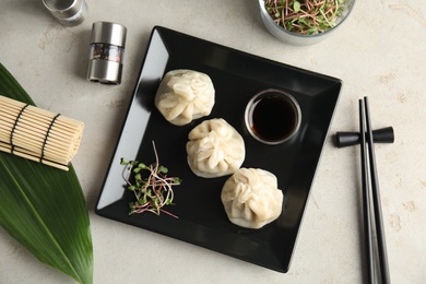 Photo of Plate with tasty baozi dumplings, sprouts and soy sauce served on table, top view