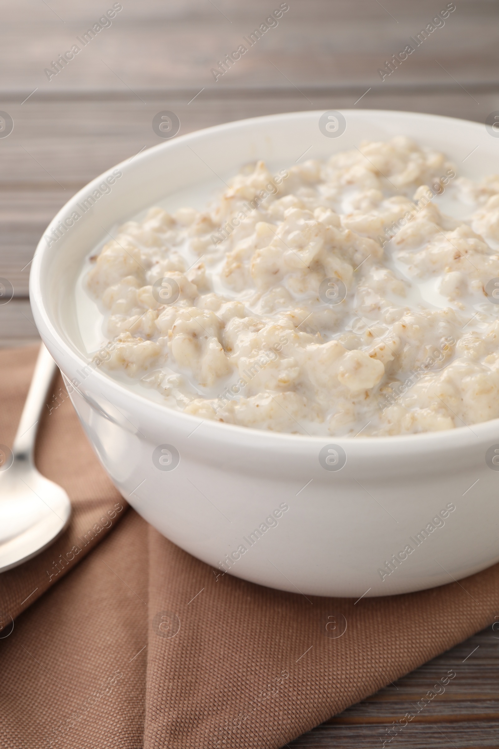 Photo of Tasty boiled oatmeal in bowl on table, closeup