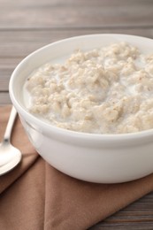 Tasty boiled oatmeal in bowl on table, closeup