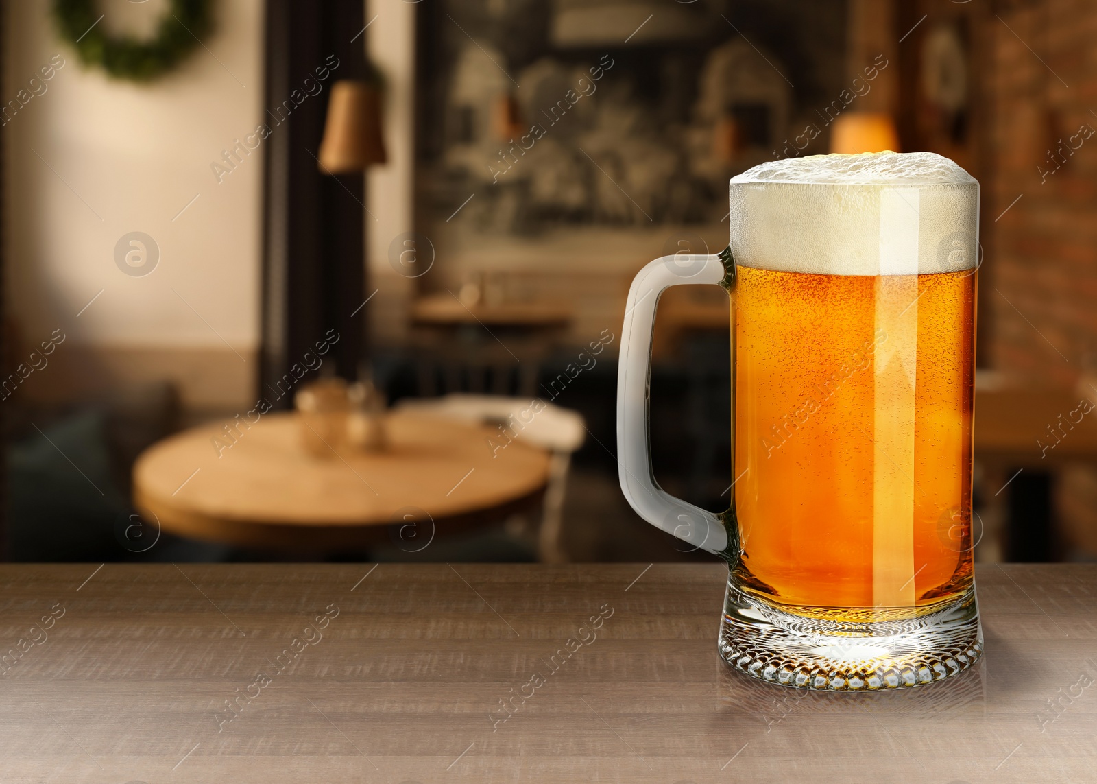 Image of Glass mug with cold tasty beer on wooden table in pub, space for text