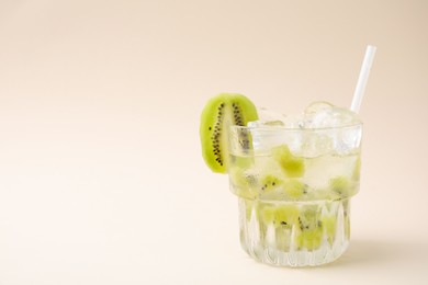 Glass of refreshing drink with kiwi on beige background, space for text