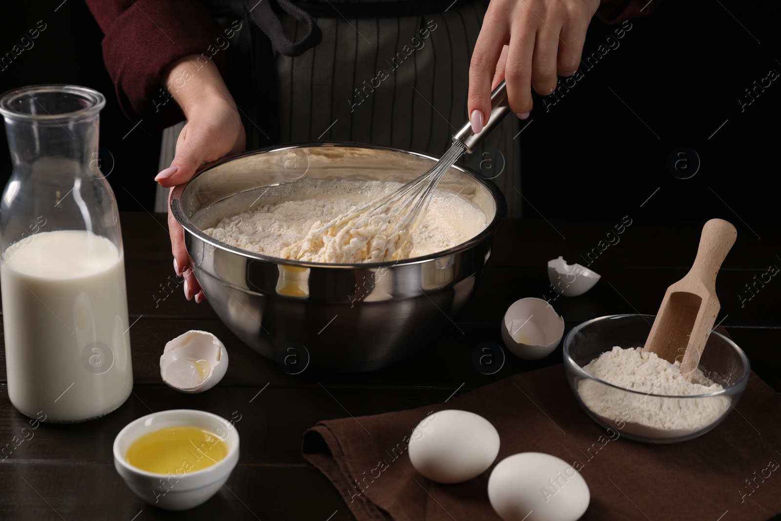 Photo of Woman making dough with whisk in bowl at table, closeup