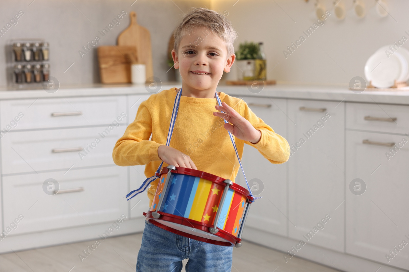 Photo of Little boy playing toy drum in kitchen