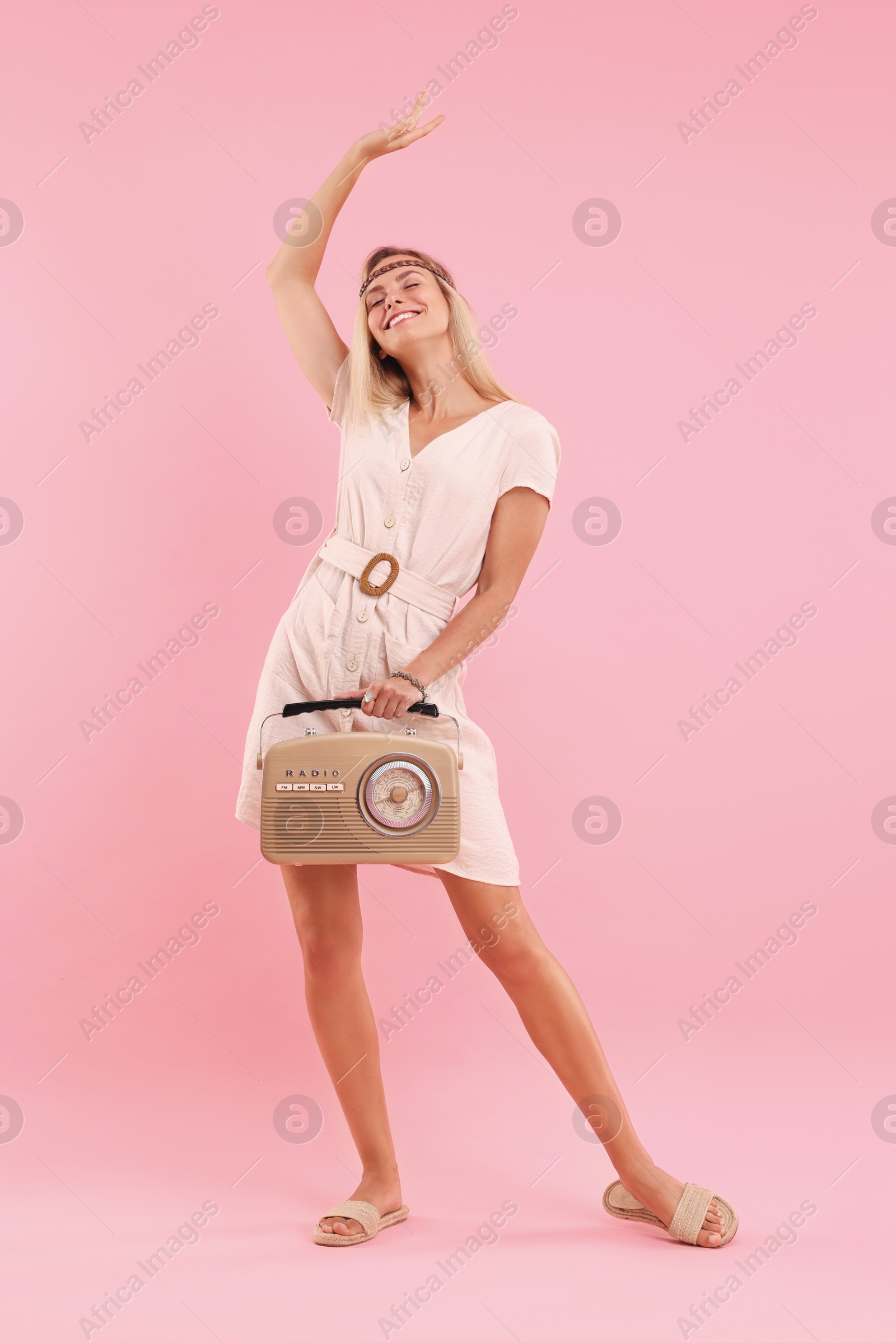Photo of Happy hippie woman with retro radio receiver on pink background