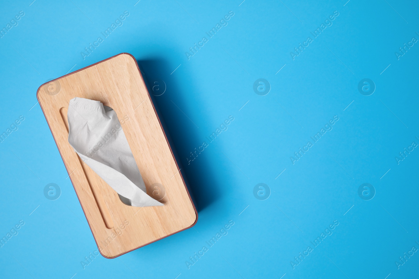 Photo of Holder with paper tissues on light blue background, top view. Space for text