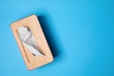 Photo of Holder with paper tissues on light blue background, top view. Space for text