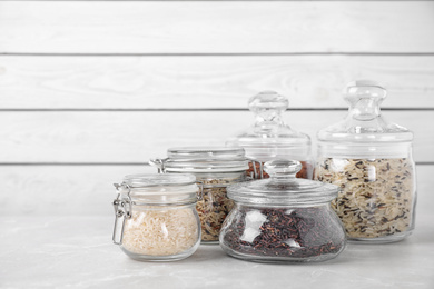 Photo of Brown and polished rice in glass jars on white table