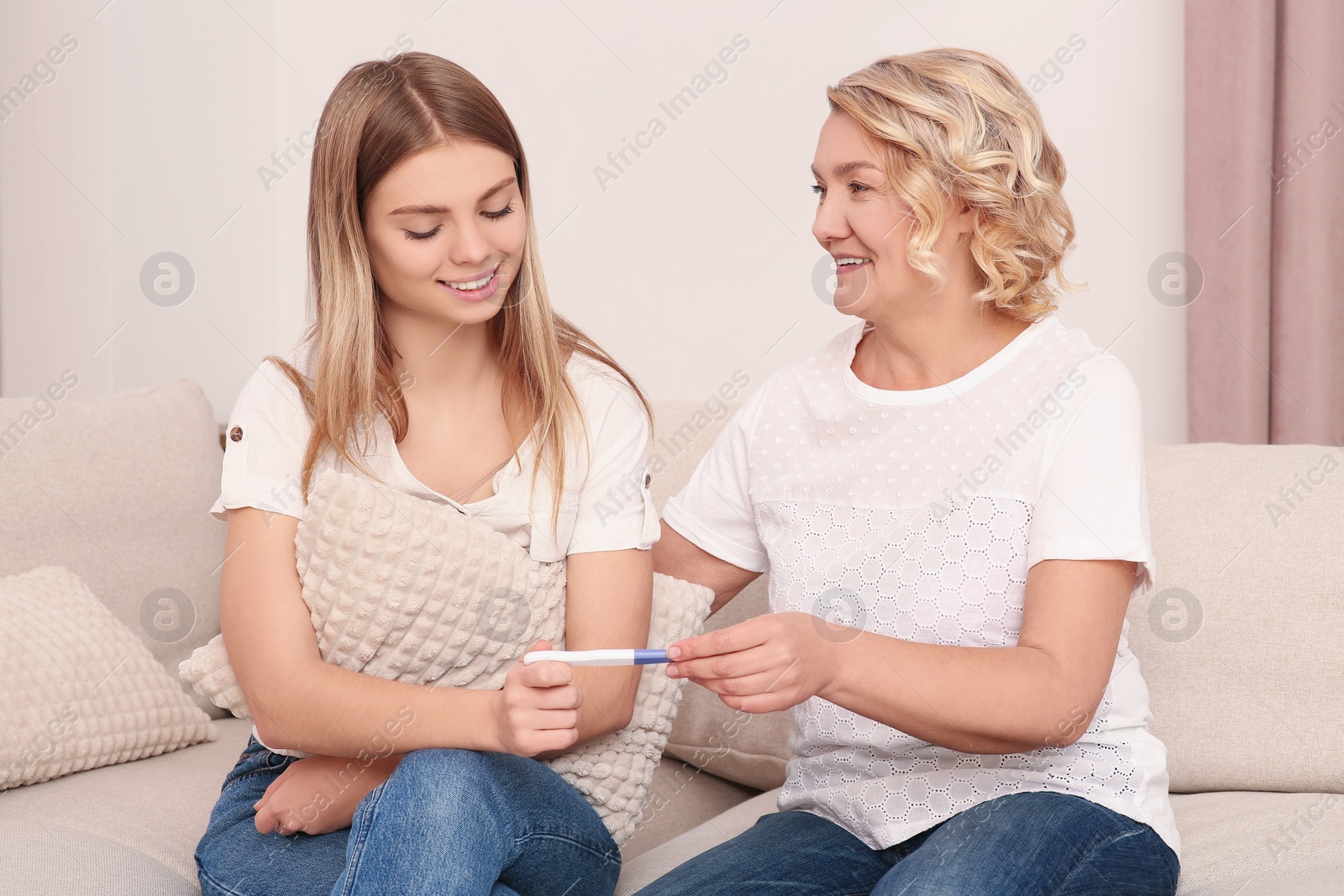 Photo of Young woman showing her mother pregnancy test at home. Grandparent reaction to future grandson