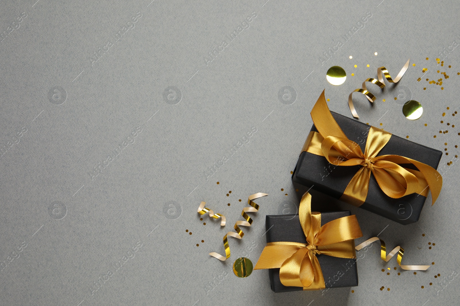 Photo of Two gift boxes. confetti and streamers on grey background, flat lay. Space for text