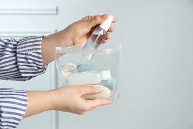 Photo of Woman packing cosmetic travel kit indoors, closeup. Space for text