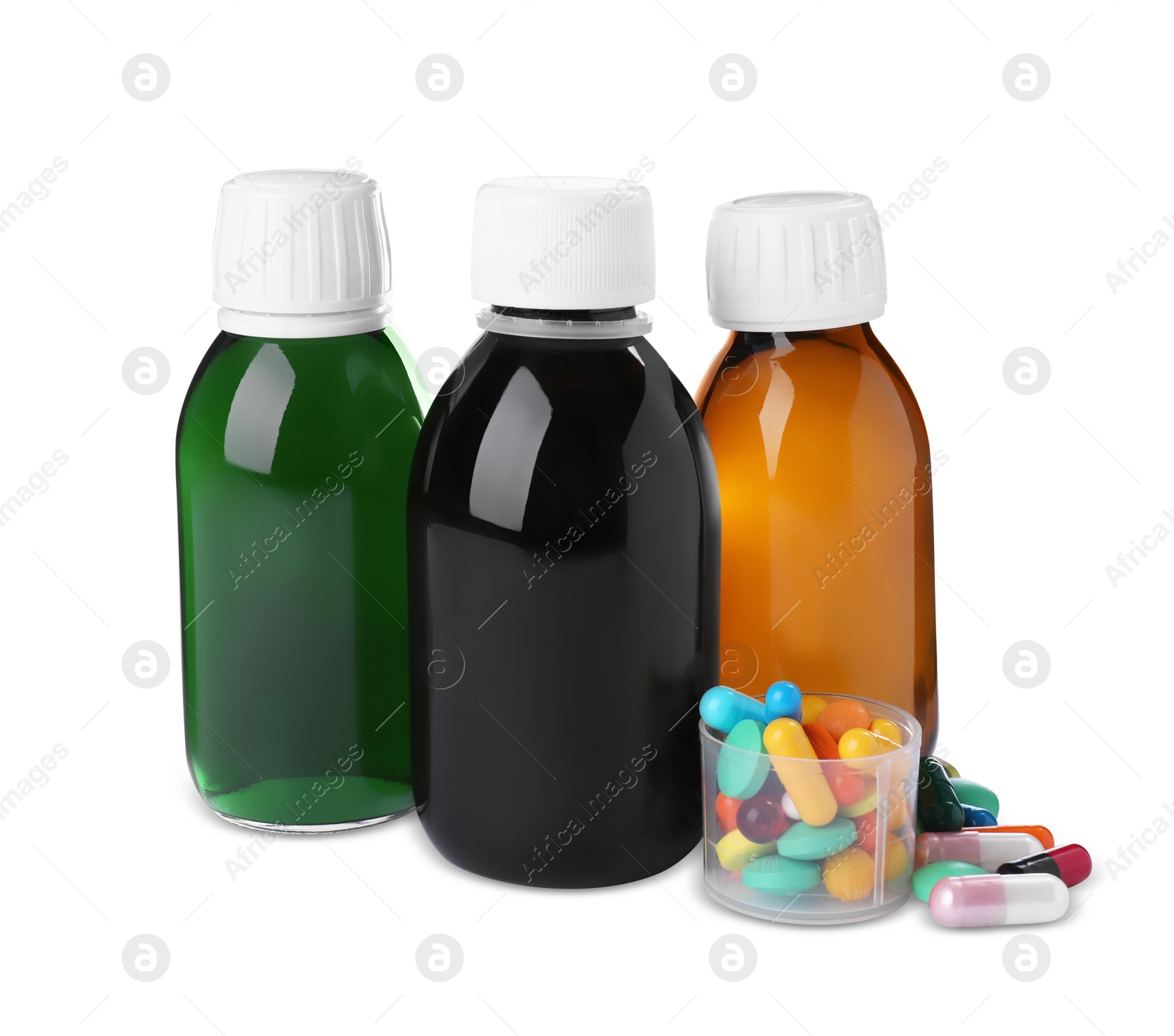 Photo of Bottles of syrups, measuring cup with pills on white background. Cough and cold medicine