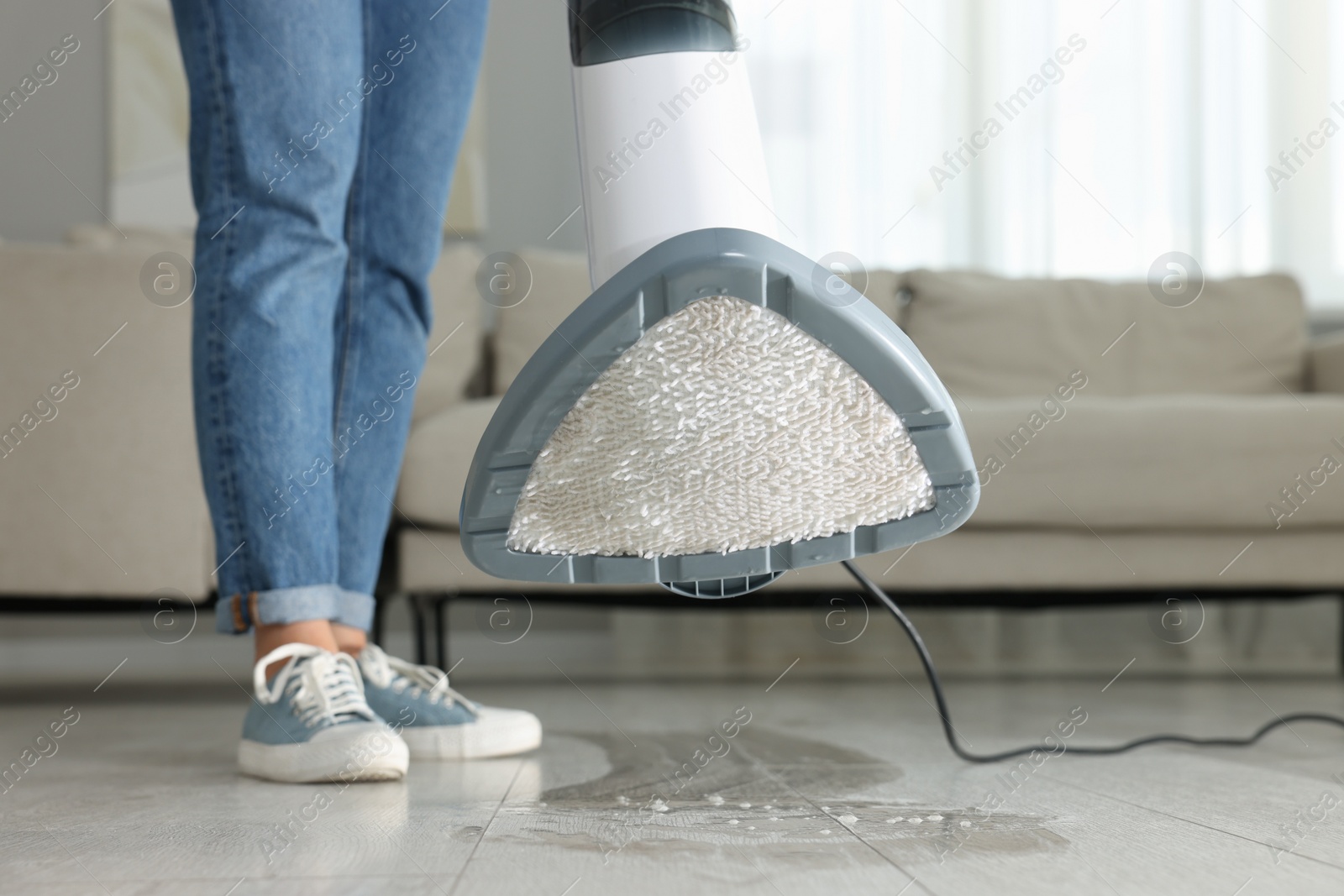 Photo of Woman cleaning floor with steam mop at home, closeup