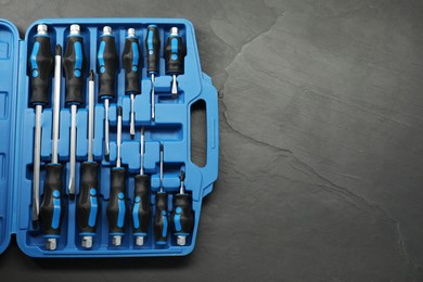 Photo of Set of screwdrivers in open toolbox on dark textured table, top view. Space for text