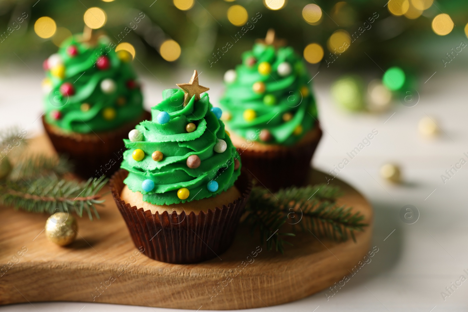 Photo of Tasty Christmas cupcakes on wooden board, closeup. Space for text