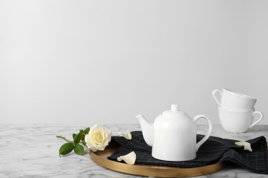 Photo of Tray with teapot and rose on table against light background