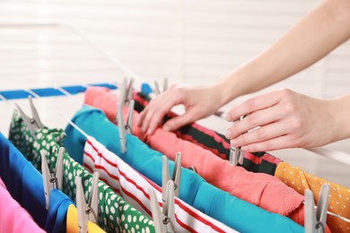 Woman hanging clean laundry on drying rack indoors, closeup