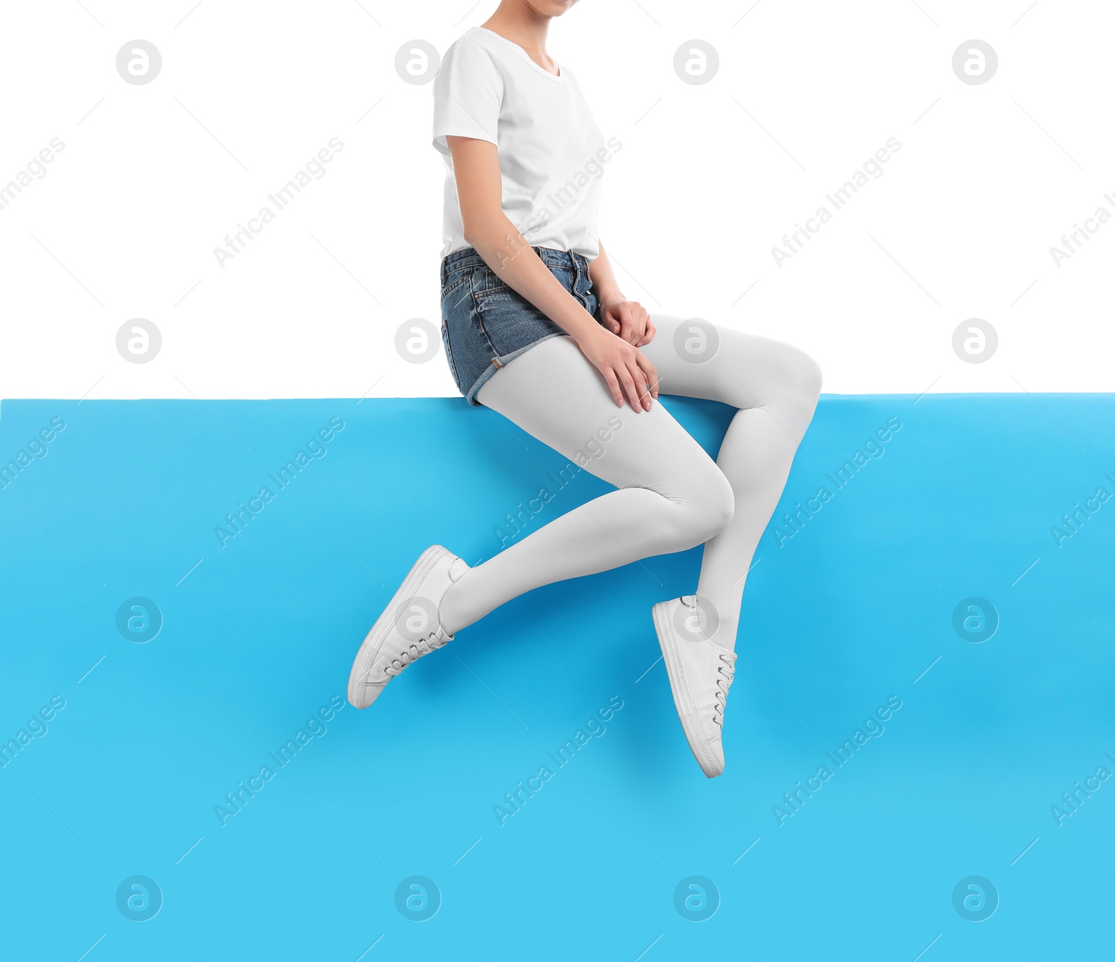 Photo of Woman wearing bright tights and stylish shoes sitting on color background, closeup