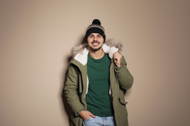 Young man wearing warm clothes on color background. Ready for winter vacation