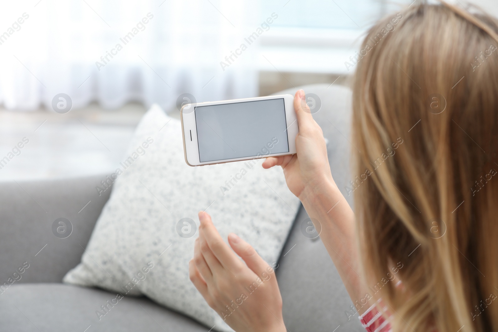 Photo of Young woman using video chat on smartphone in living room, closeup. Space for design