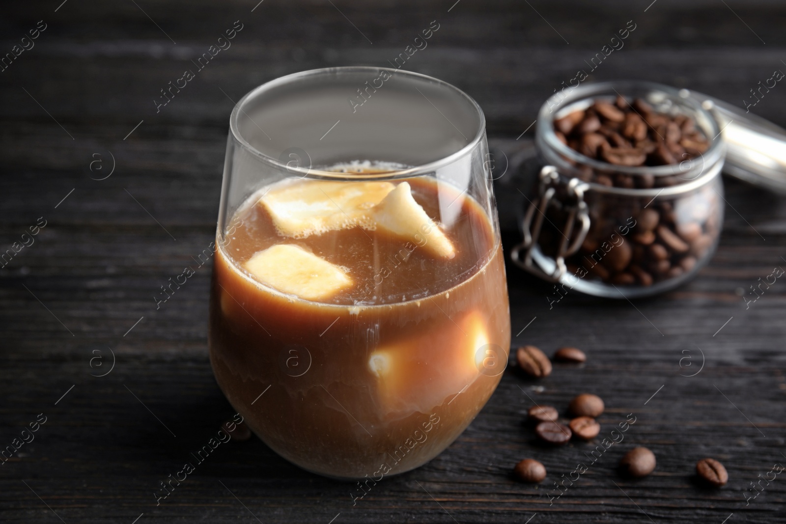 Photo of Coffee drink with milk ice cubes and beans on dark background
