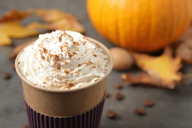 Photo of Paper cup with tasty pumpkin spice latte on grey table, closeup