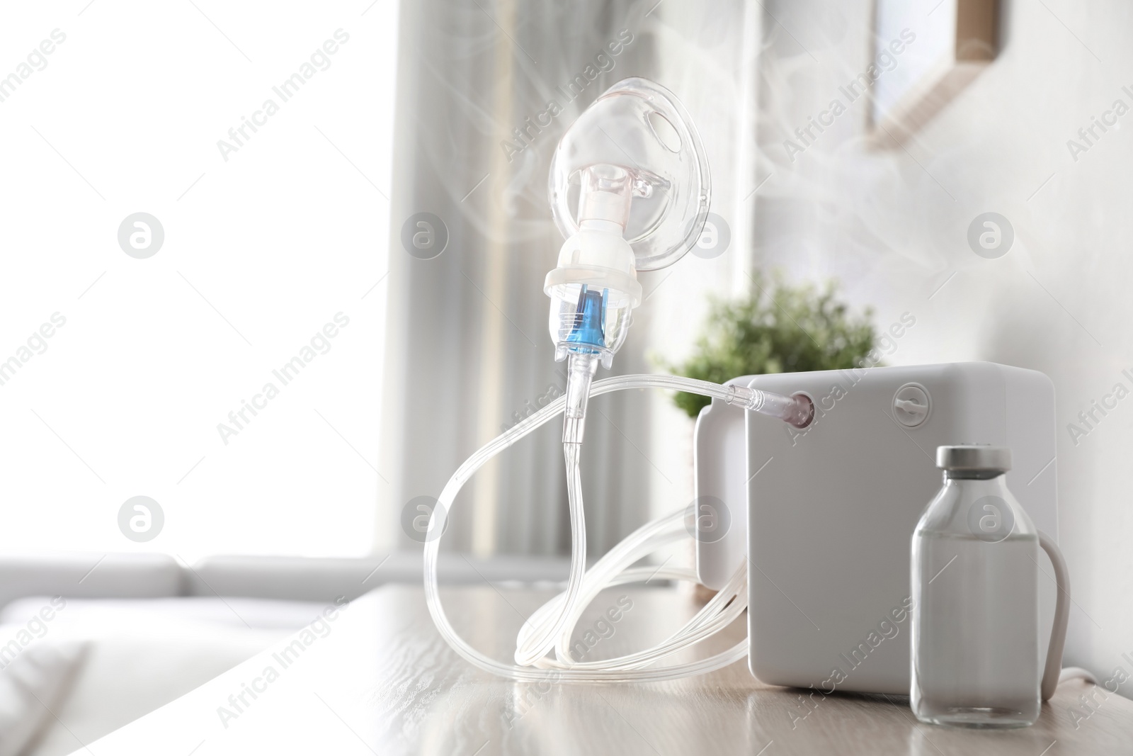 Image of Modern nebulizer with face mask on table indoors. Inhalation equipment