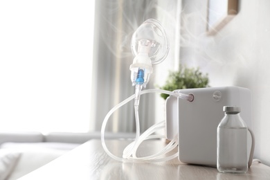 Image of Modern nebulizer with face mask on table indoors. Inhalation equipment