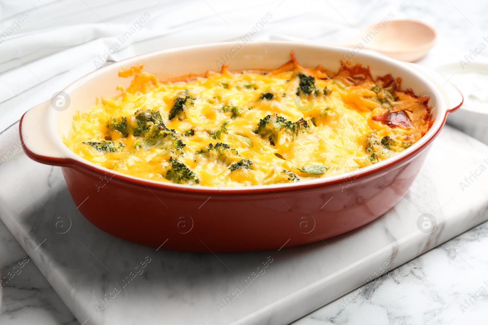 Photo of Tasty broccoli casserole in baking dish on white marble table