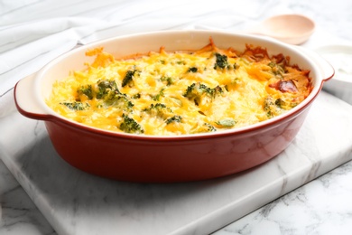 Photo of Tasty broccoli casserole in baking dish on white marble table