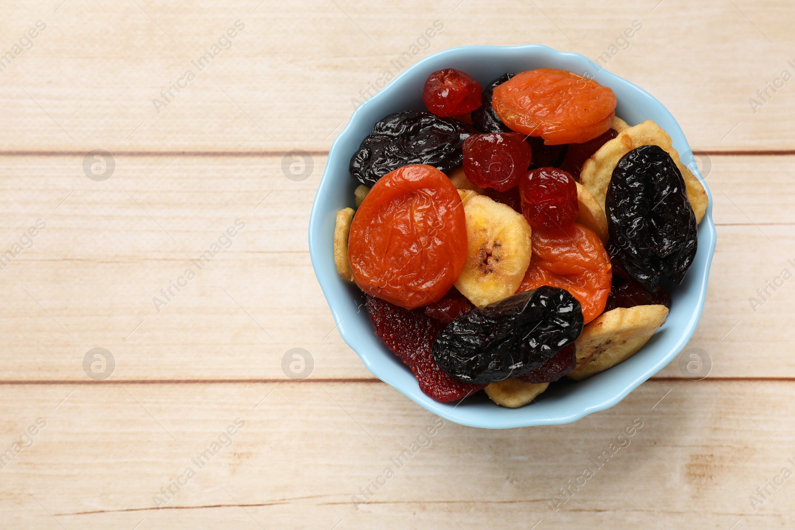 Photo of Mix of delicious dried fruits on white wooden table, top view. Space for text