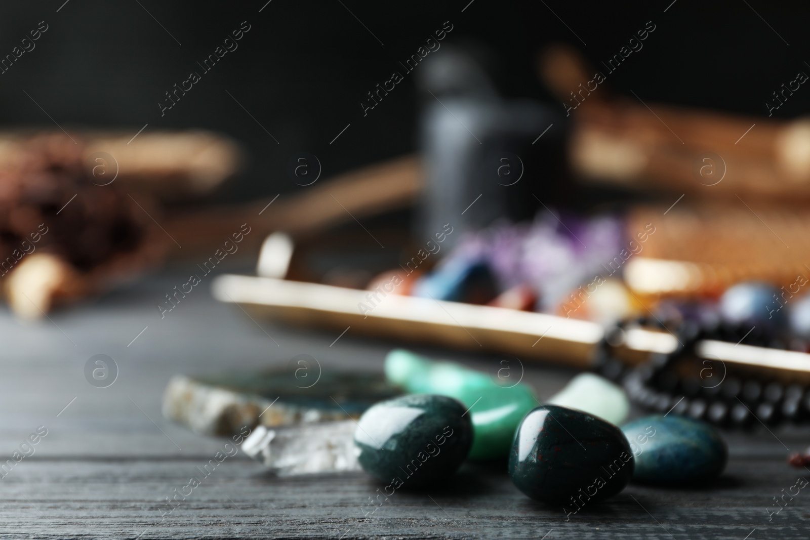 Photo of Many different gemstones on black wooden table