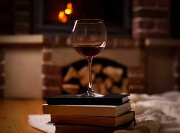 Glass of wine on books near fireplace indoors