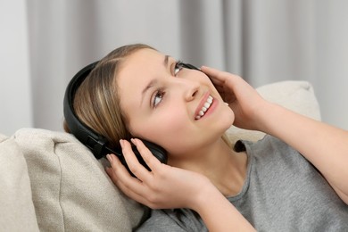 Photo of Teenage girl listening to music with headphones indoors