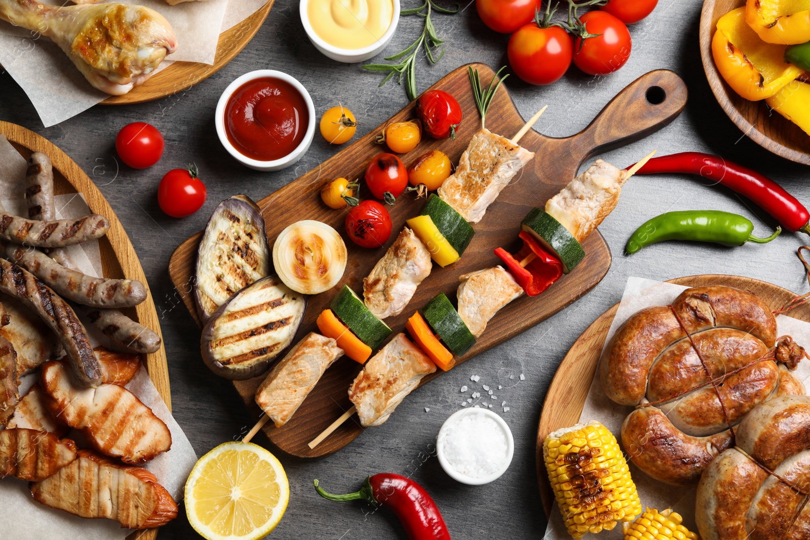 Photo of Flat lay composition with barbecued meat and vegetables on grey table