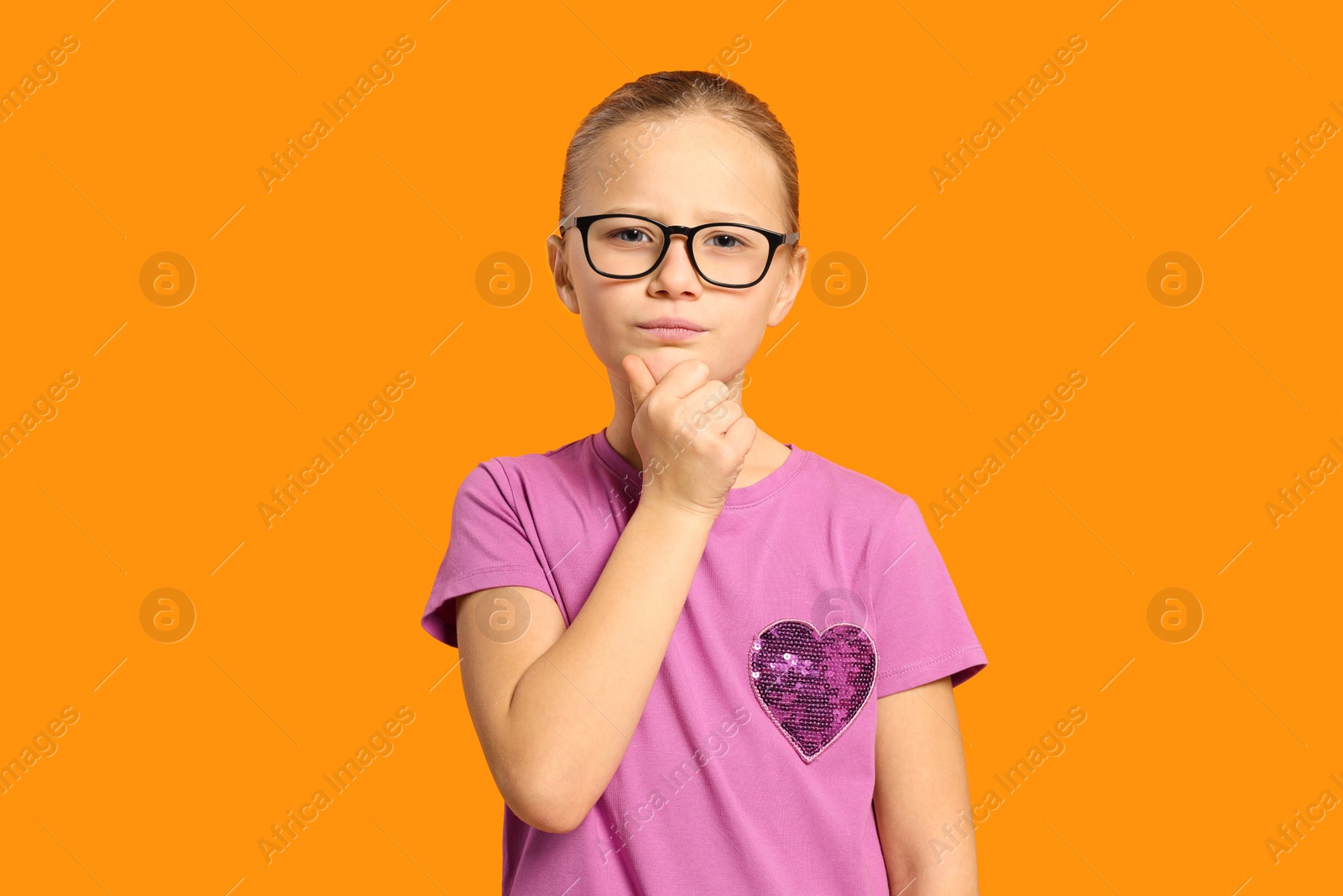 Photo of Portrait of cute girl in glasses on orange background